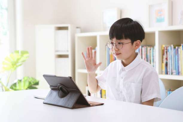 태블릿으로 선생님과 인사하며 학습하는 학생